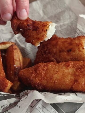 beer battered fish broken open to expose white flesh.