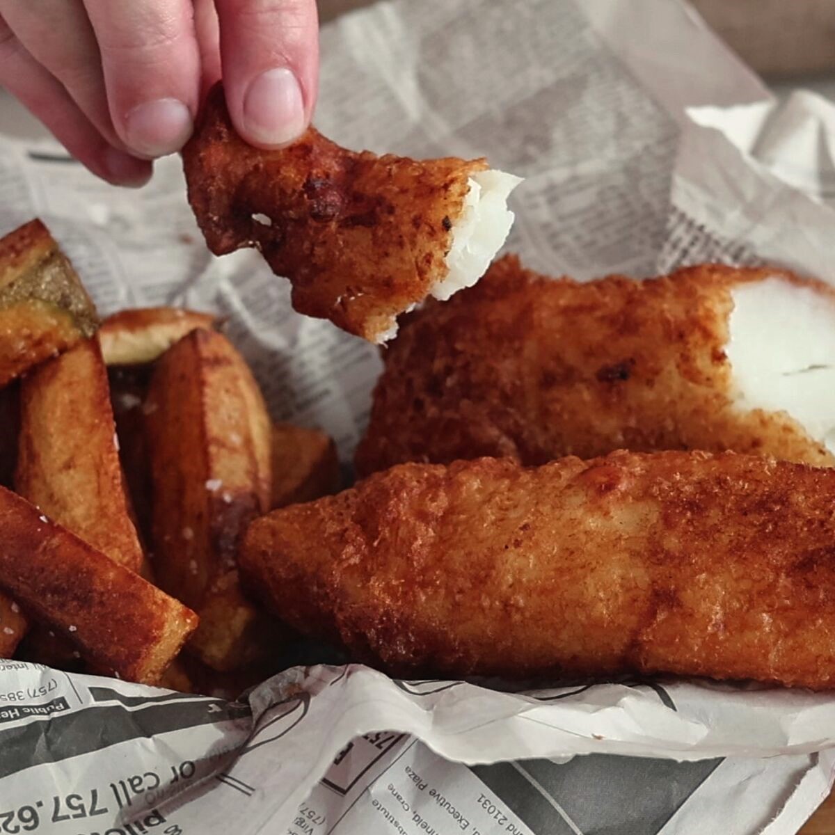beer battered fish broken open to expose white flesh.