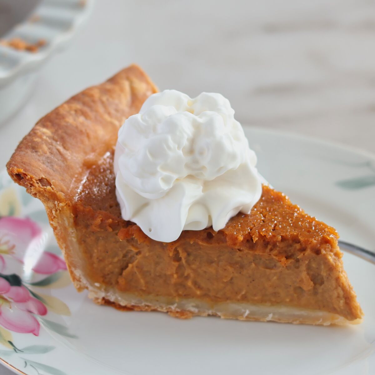 slice of pumpkin pie with whipped cream on top.