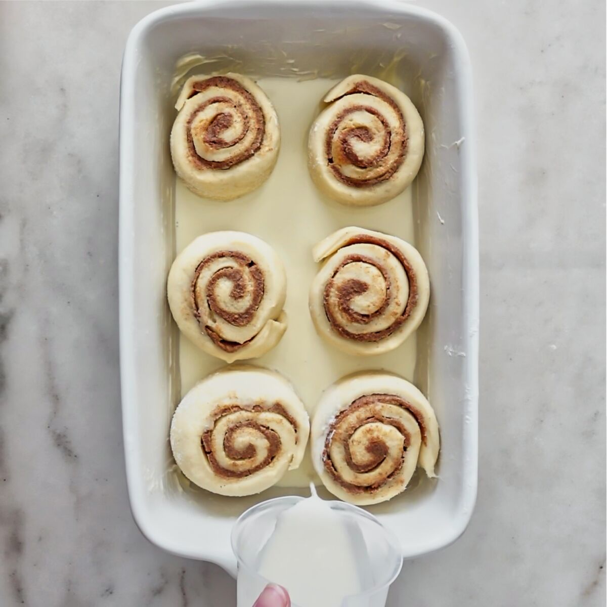 pouring heavy cream into bottom of baking dish.
