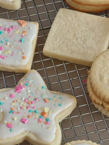star and square sugar cookies on wire rack with icing and sprinkles on half.