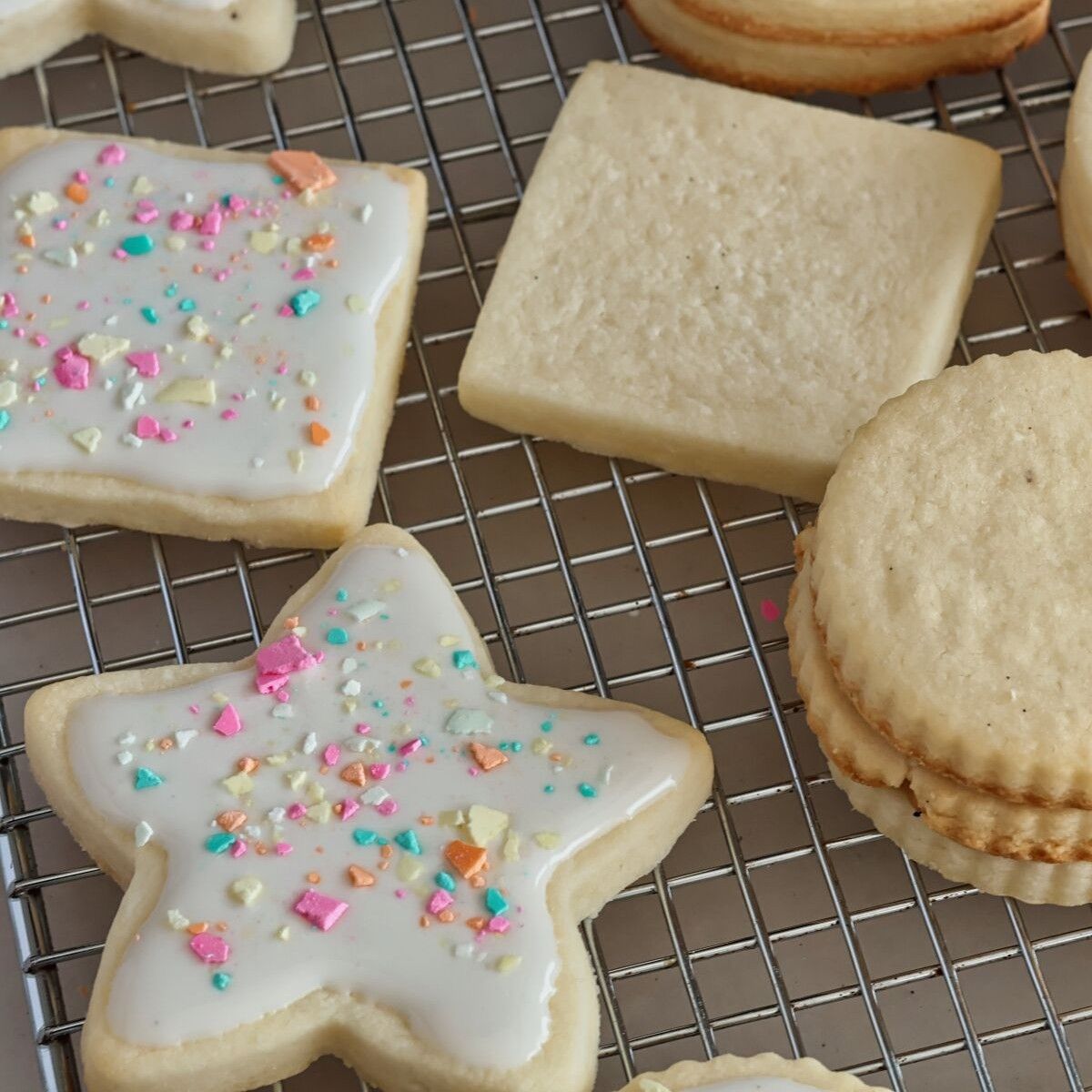 star and square sugar cookies on wire rack with icing and sprinkles on half.