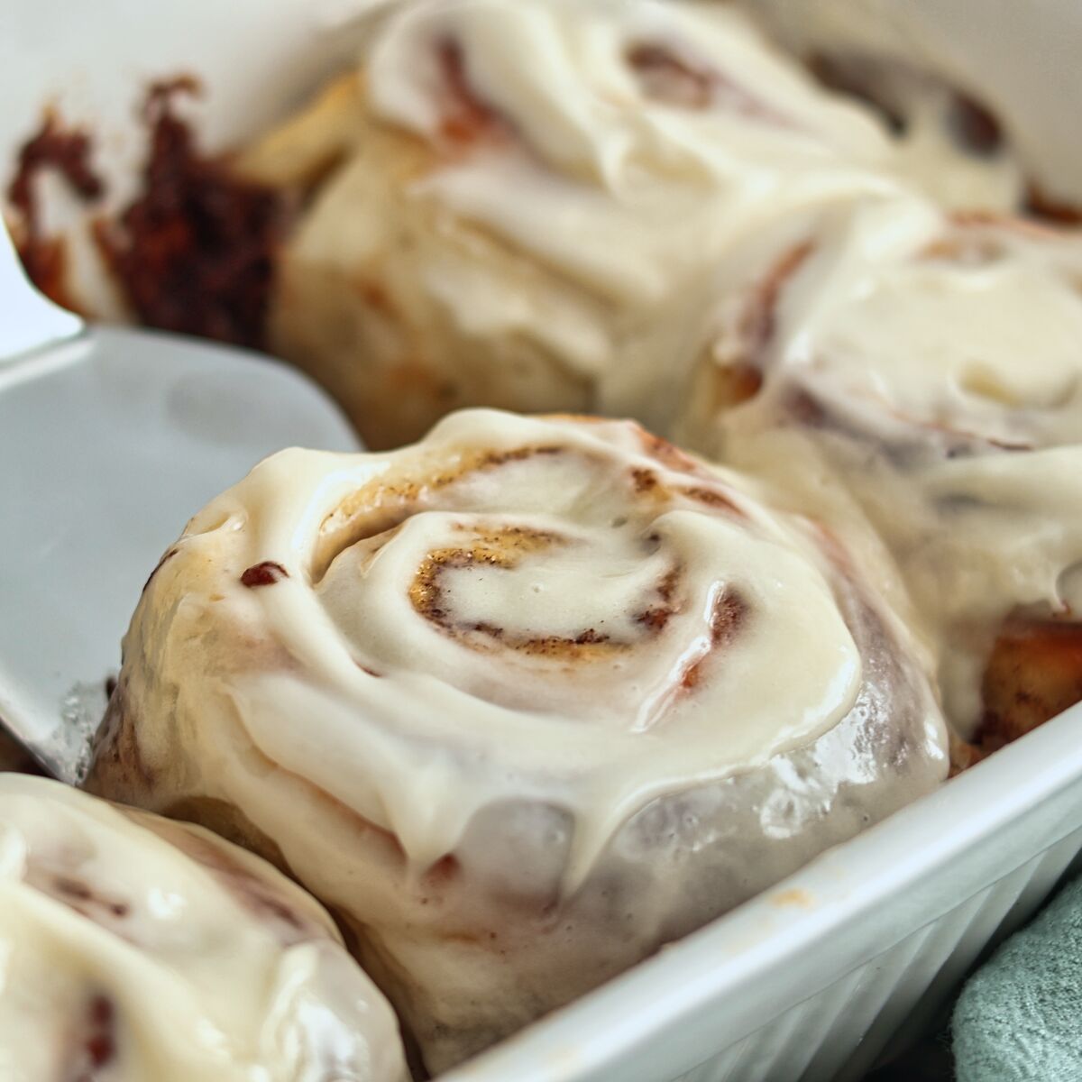 sliding a metal spatula under a cinnamon roll.