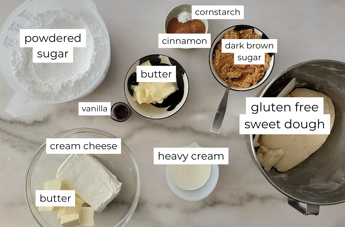 cinnamon roll ingredients measured out and labeled on marble counter.