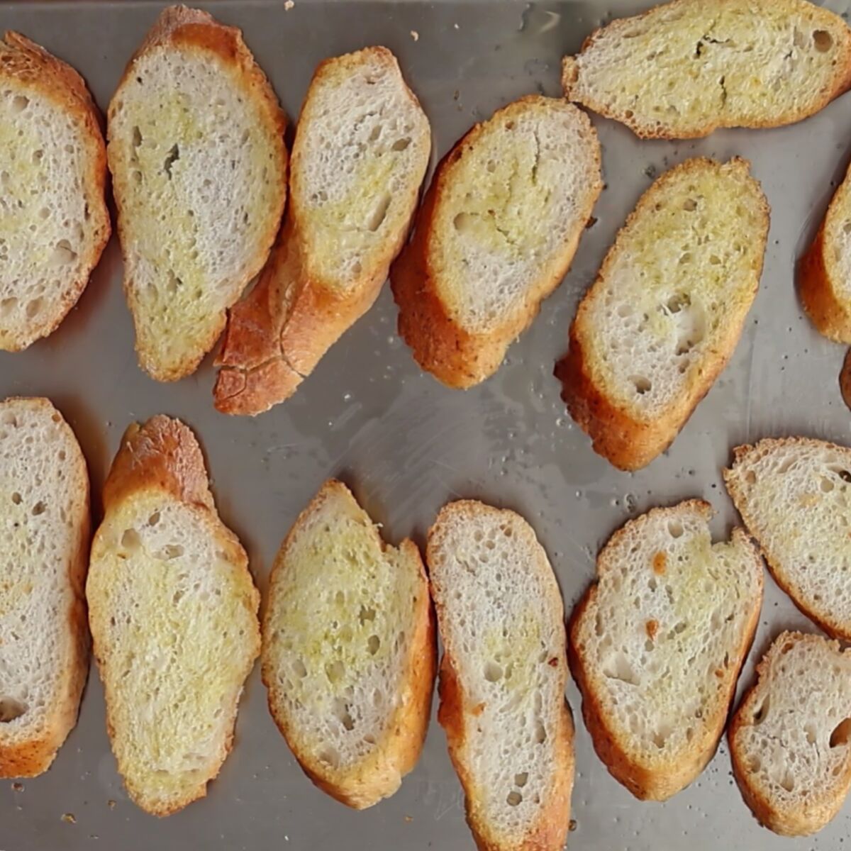 crostini slices on stainless steel baking sheet.