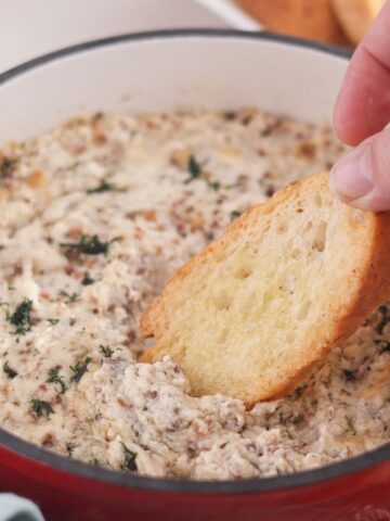 dipping crostini into hot dip in red cast iron skillet.