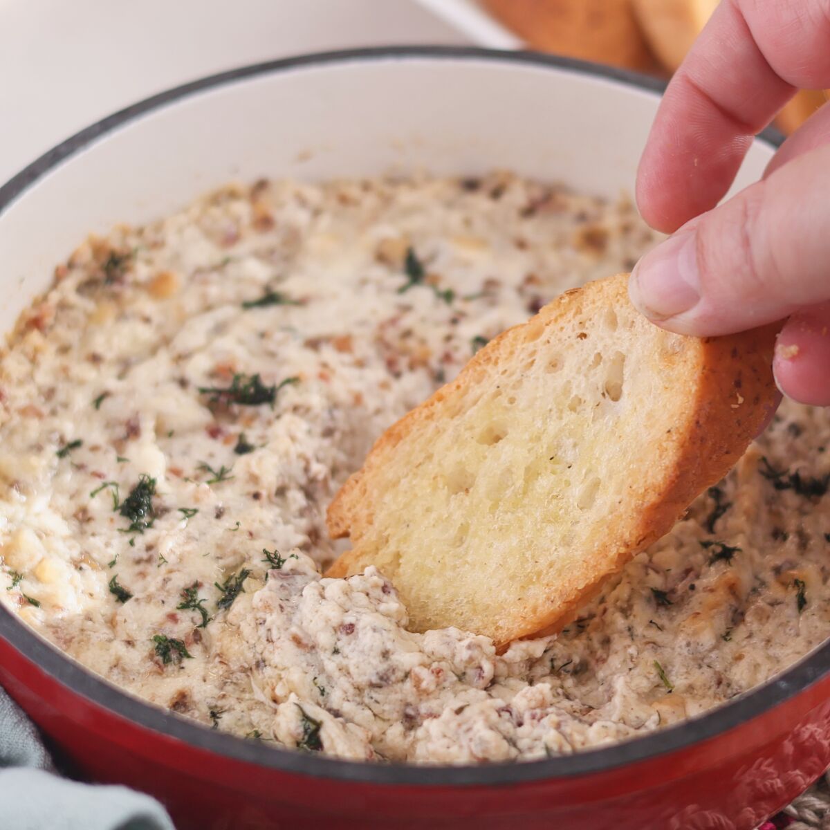 dipping crostini into hot dip in red cast iron skillet.