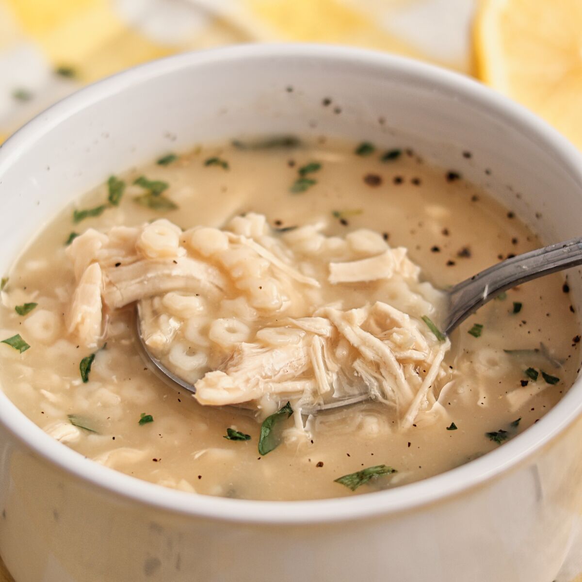 white bowl filled with lemon chicken pastina soup.