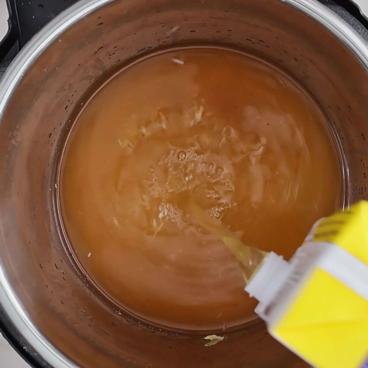 pouring chicken stock into instant pot.