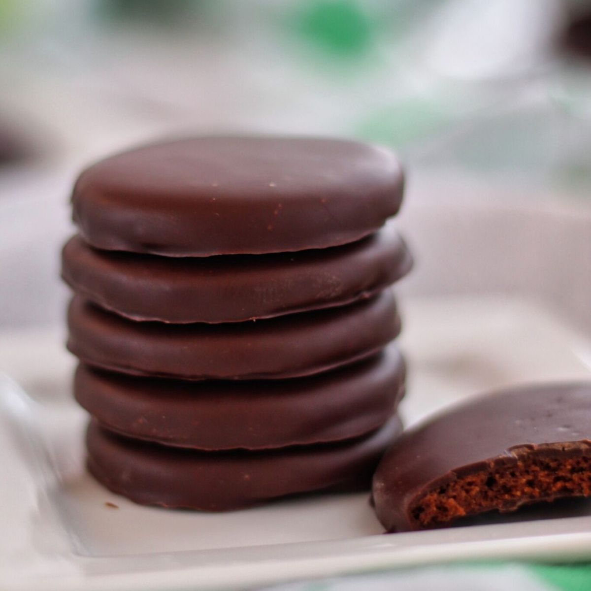 stack of thin mints on white square plate with one broken in half.