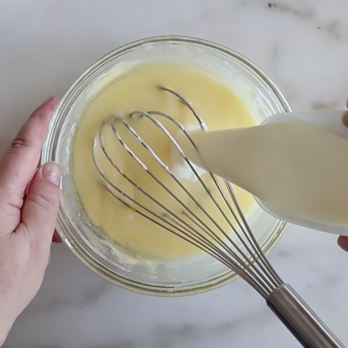 pouring milk into egg/sugar mixture in small glass bowl.