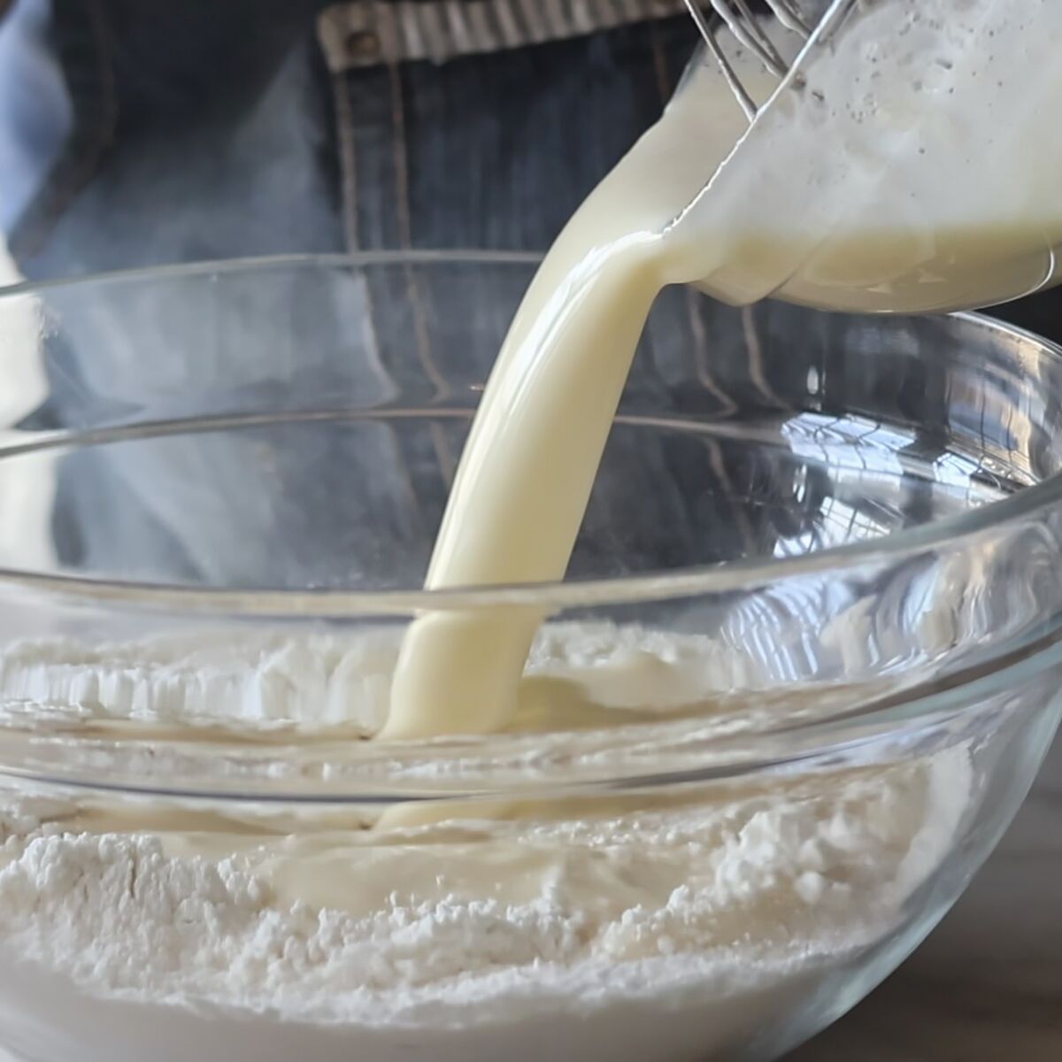pouring wet ingredients into dry ingredients in large glass bowl.