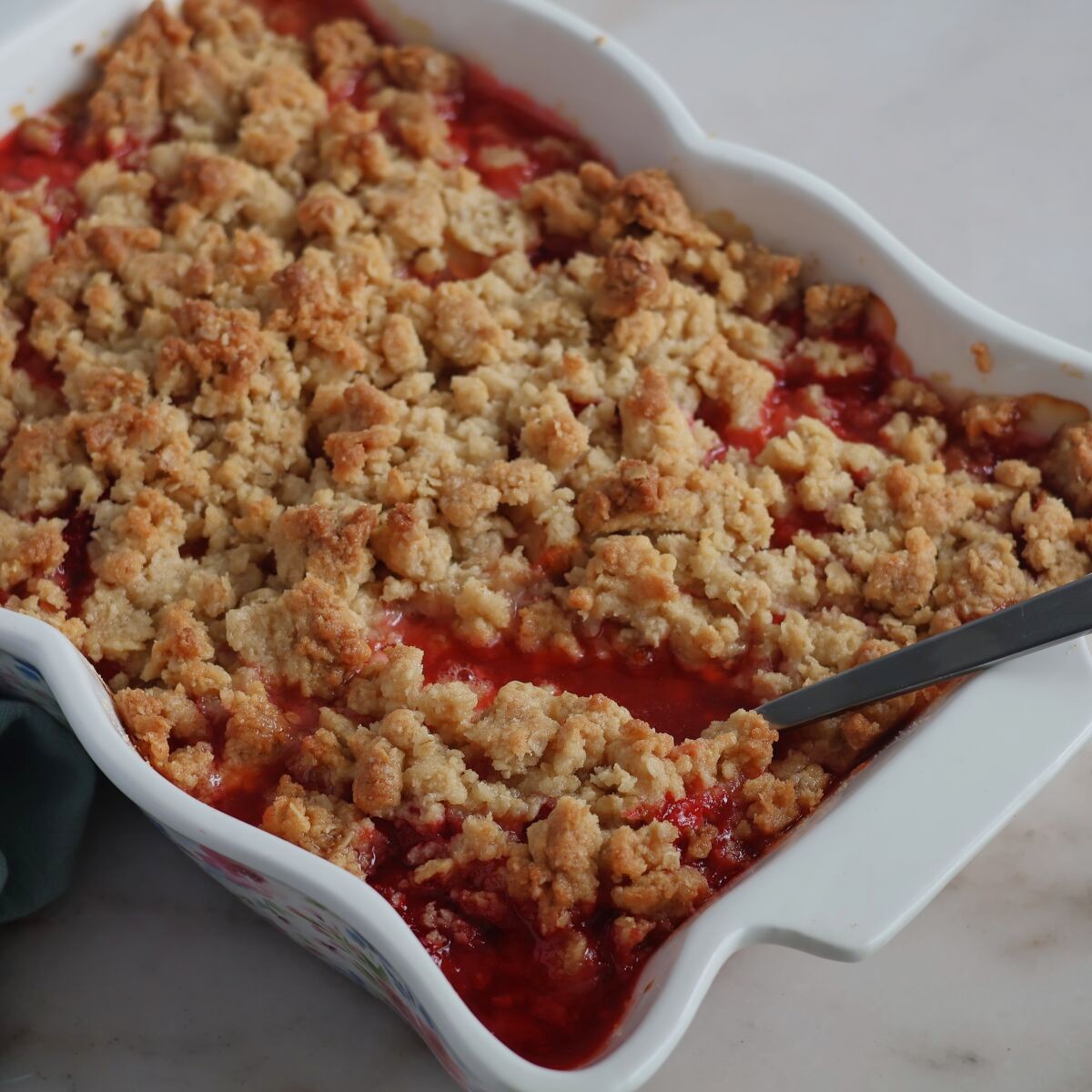 strawberry rhubarb crisp in white casserole dish.