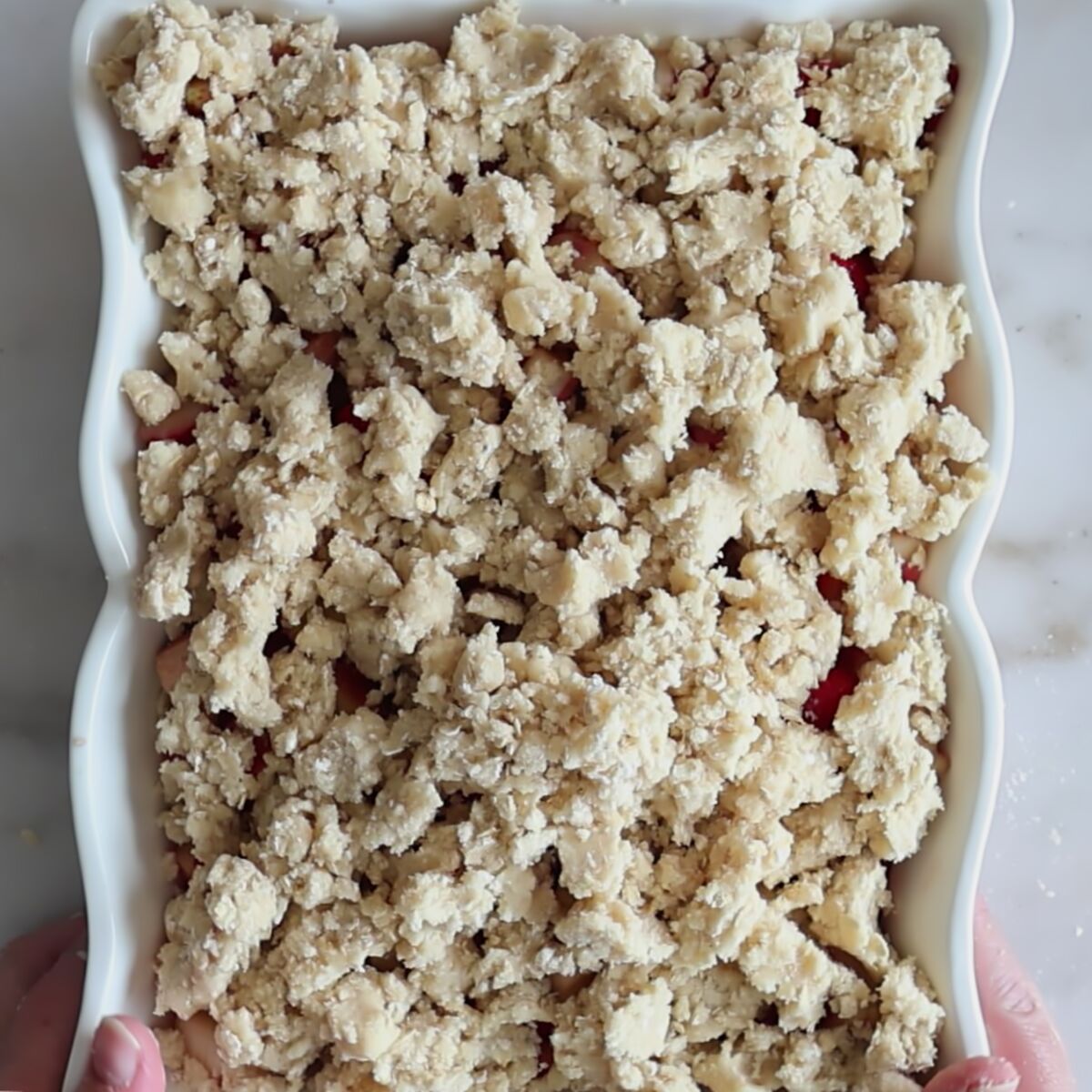 strawberry rhubarb mixture completely covered with crisp crumbs and ready to bake.