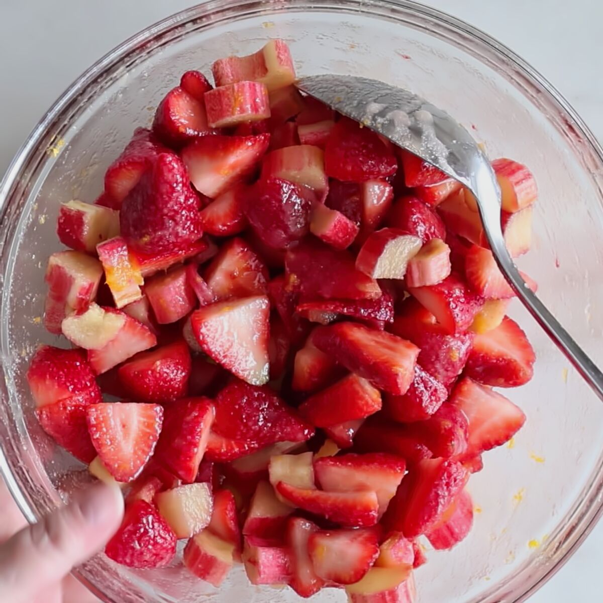 chopped strawberries and rhubarb mixed with sugar in large glass bowl.