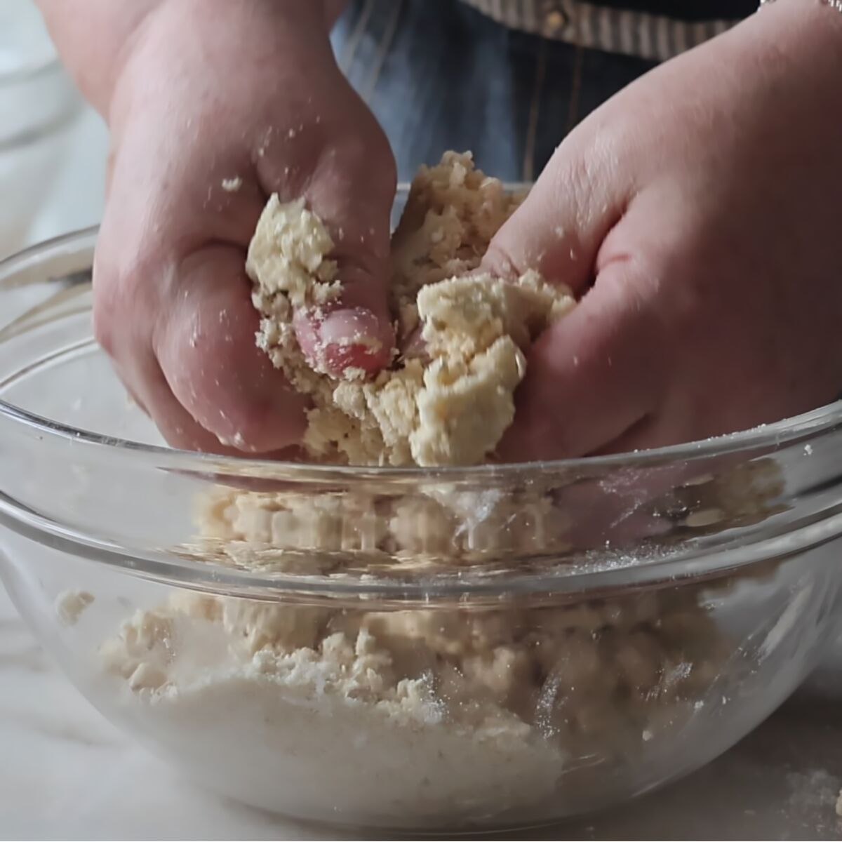 cutting butter into crisp mixture with hands in large glass bowl.
