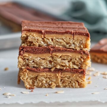 three peanut butter oatmeal bars stacked on top of each other neatly with a green towel in the background.