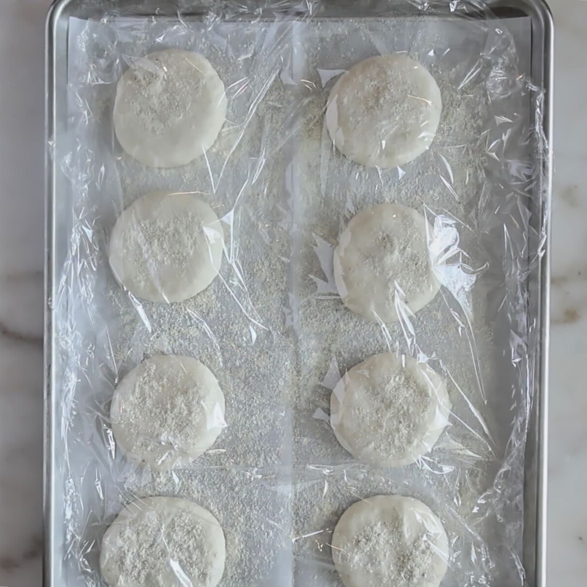 flattened rolls on baking sheet covered with plastic wrap.