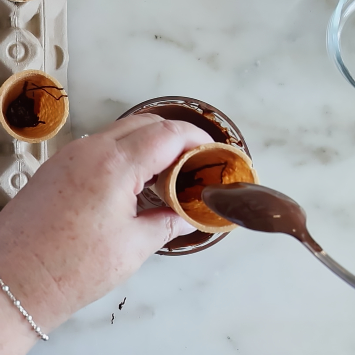spooning melted chocolate into ice cream cone.