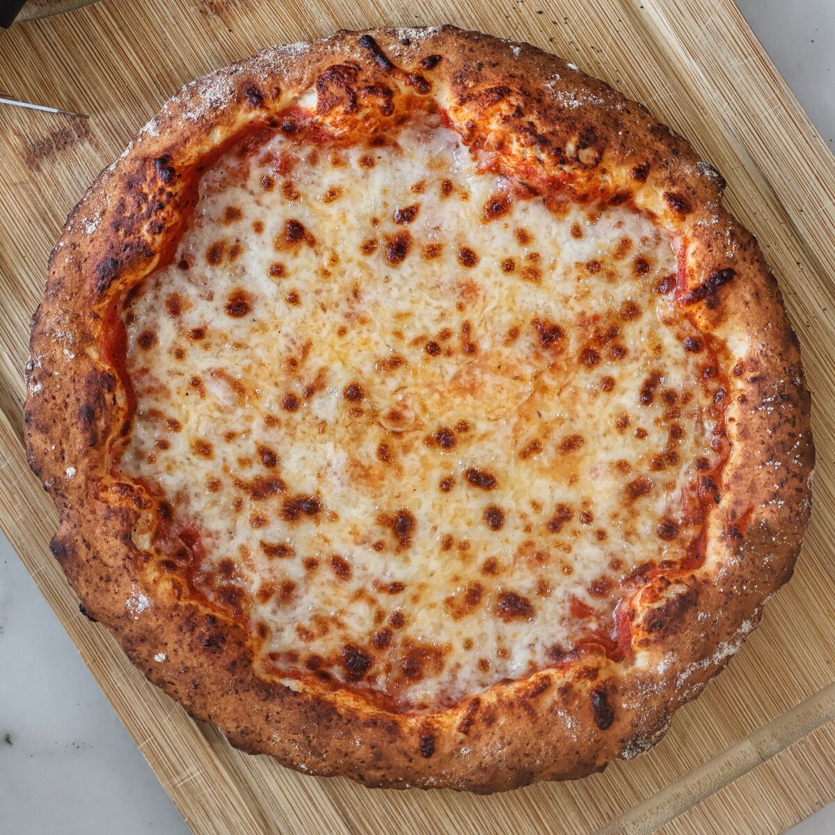 whole baked pizza on cutting board.