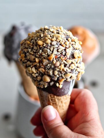 holding one ice cream drumstick in hand.