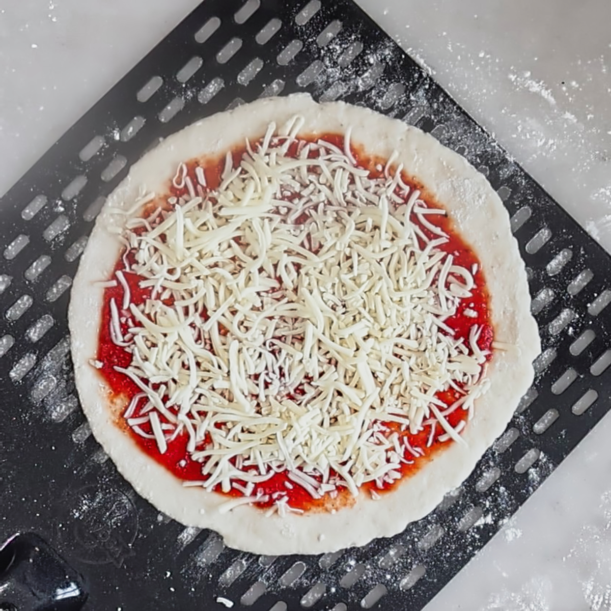 unbaked pizza on nonstick perforated pizza peel.