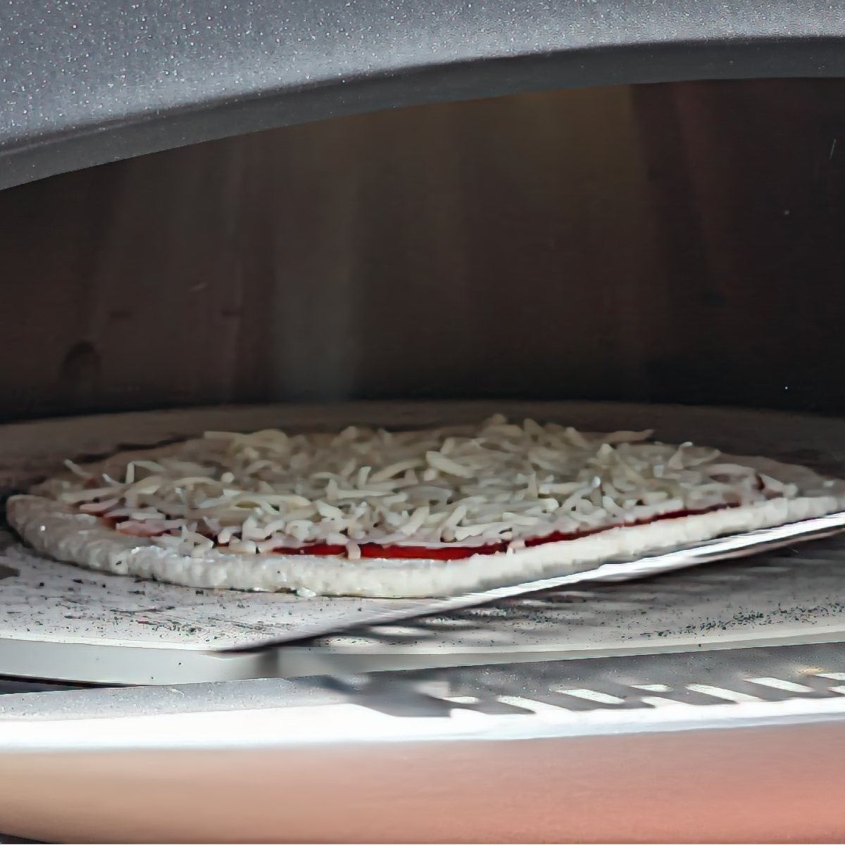 sliding pizza off peel onto stone in pizza oven.