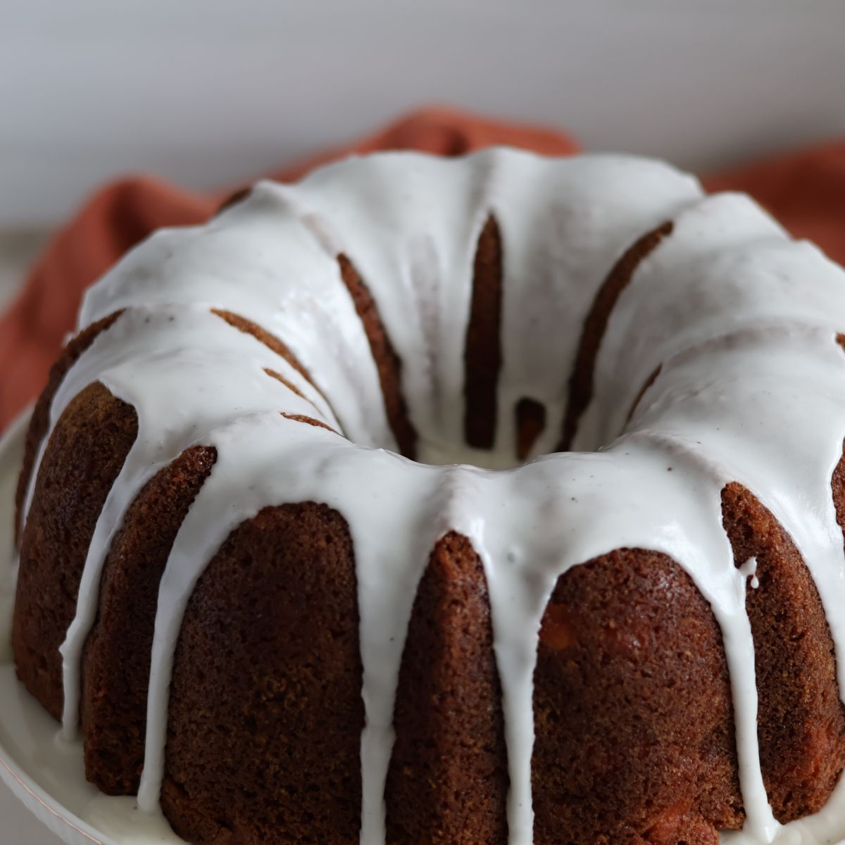 slice of gluten free apple bundt cake on white plate with red apple in background
