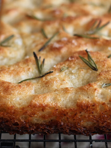 whole focaccia loaf on black wire rack.