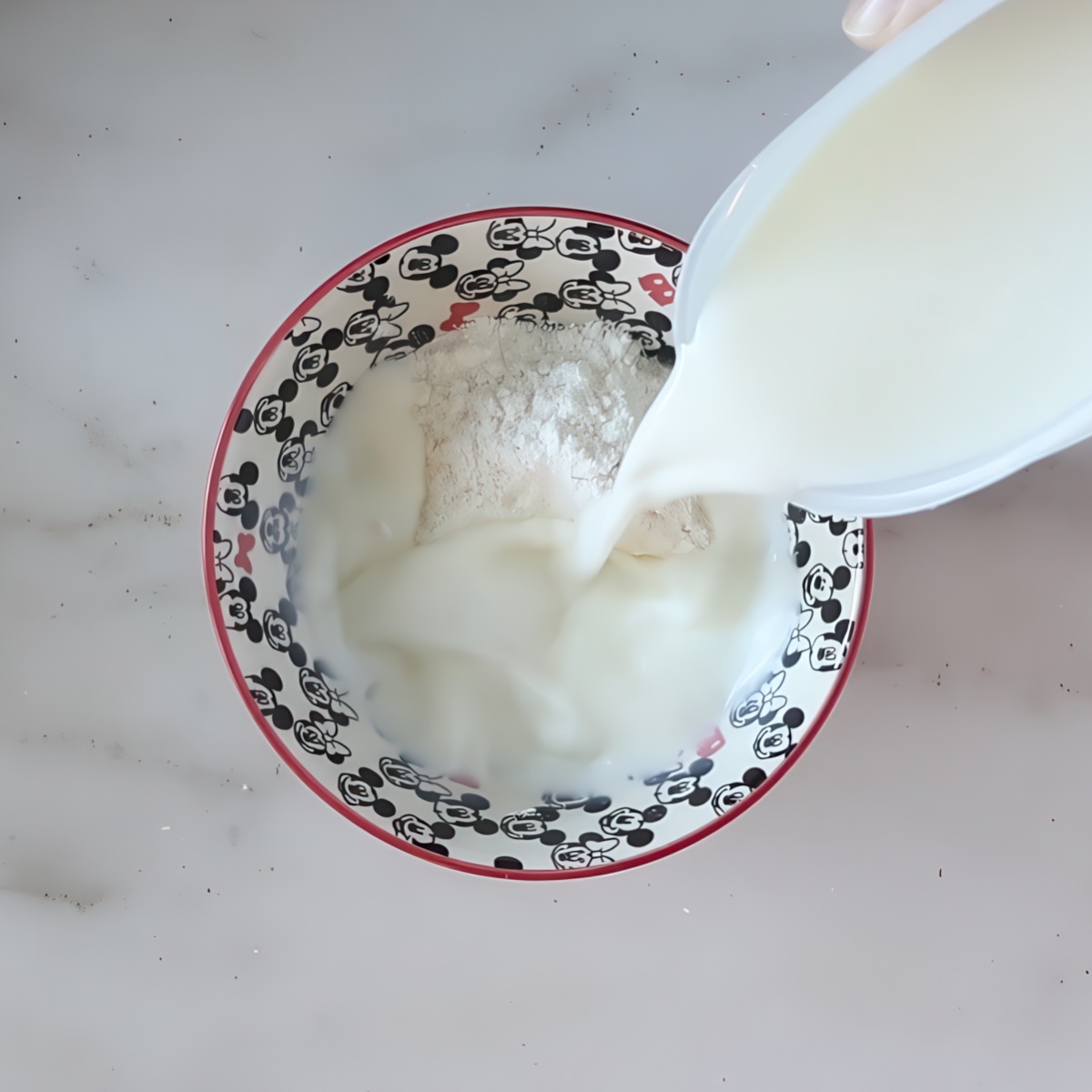 pouring milk into flour in small bowl.