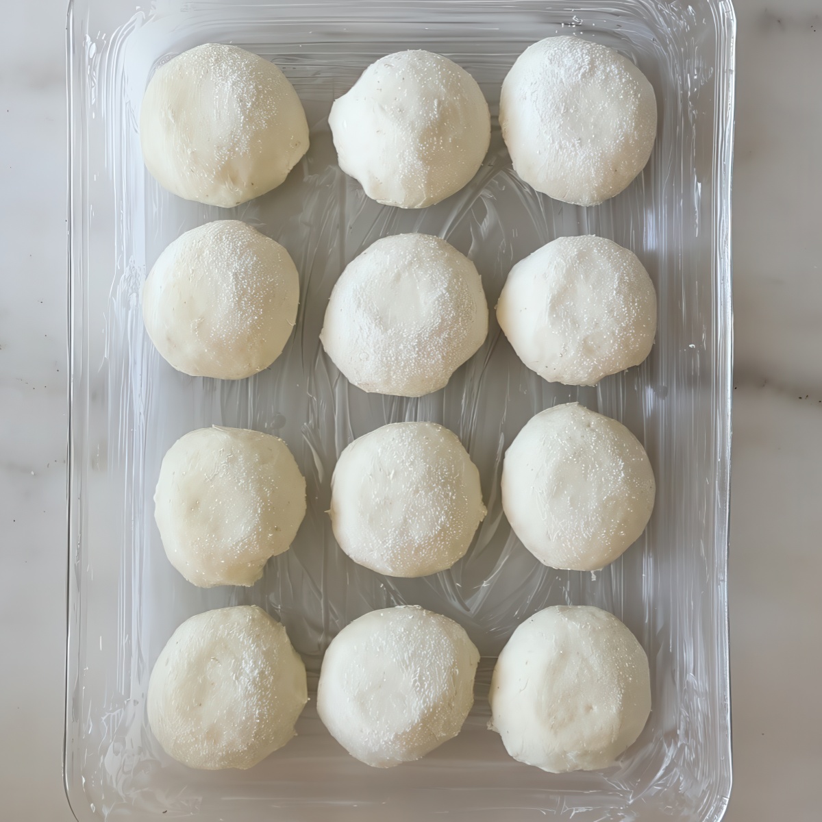 unrisen round shaped rolls in glass pan.