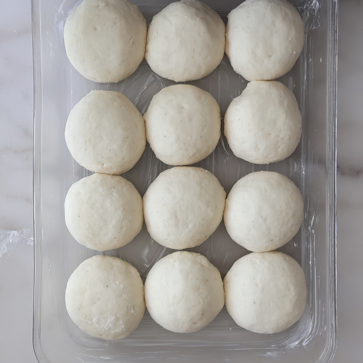 risen round rolls in glass rectangular pan.