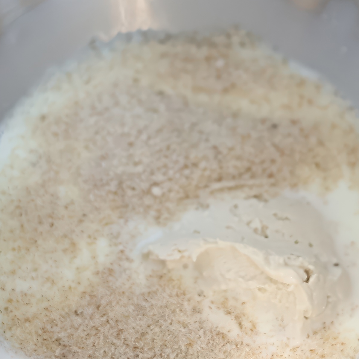psyllium husks and sourdough starter in milk in stainless steel bowl.