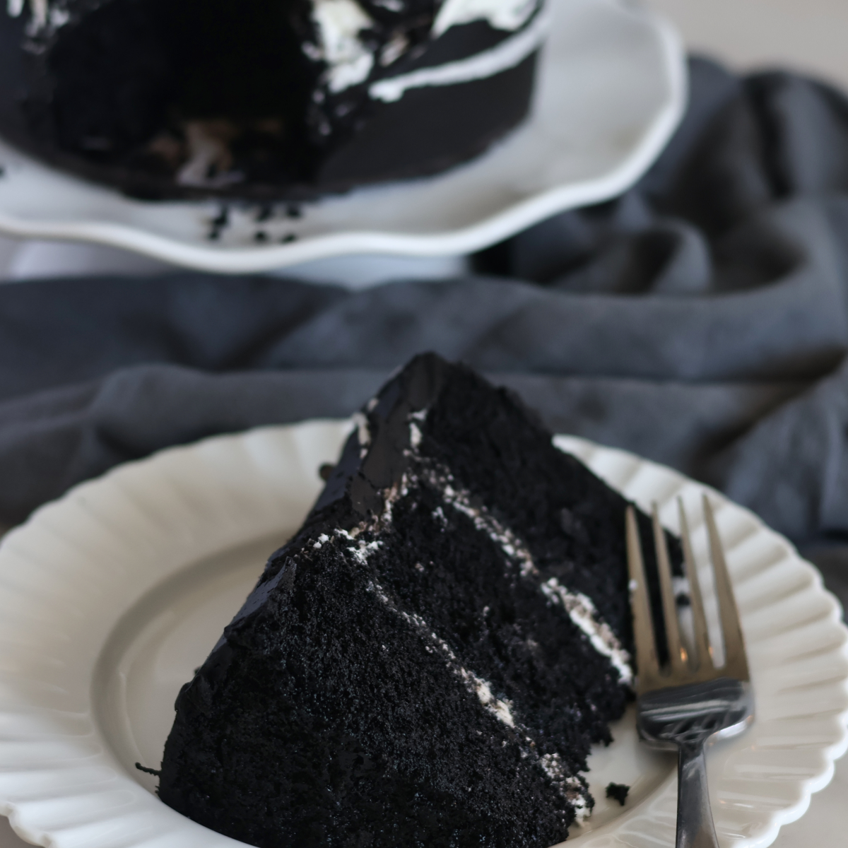 slice of black velvet cake on white plate.